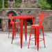 A red metal table with two red chairs on an outdoor patio.