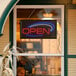 A lit up rectangular LED sign that says "Open" in red and blue letters.