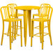 A yellow metal bar height table with four yellow chairs.