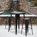 A Flash Furniture black metal bar height table with two black square stools.