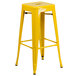 A yellow metal table with two square yellow metal stools.