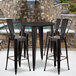 A Flash Furniture black metal bar table with four black metal chairs.