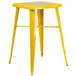 A yellow metal square stool on a bar table.