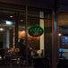 An oval LED sign that says "Pizza" on a counter in a pizza parlor.