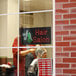 A woman getting her hair done in a hair salon under a lighted rectangular LED sign.