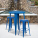 A blue metal table with two square seat backless stools on a blue metal table.