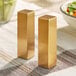 Two gold rectangular salt and pepper shakers on a table.