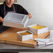 A woman putting a square cake in a white box.