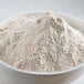 A bowl of Bob's Red Mill whole wheat flour on a white table.