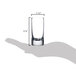 A hand holding a Stolzle New York shot glass with measurements.