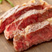 Two pieces of steak on a wooden surface.