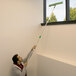 A man using an Unger UniTec telescopic pole to clean a window.