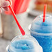 A person holding a red Choice Super Jumbo wrapped straw over a blue drink.