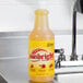 A yellow bottle of Noble Chemical Sunbright concentrated liquid dish soap on a counter.