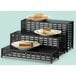 A black rectangular lattice display riser with three tiers of food plates on top.