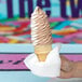 A hand holding a white Choice luncheon napkin folded into a cone with brown and white ice cream.