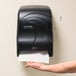 A black San Jamar Smart System paper towel dispenser on a wall.