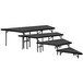 A National Public Seating black stage pie unit with metal legs and black carpet on top.