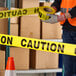 A roll of yellow caution tape being used in a warehouse setting.