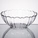 An Arcoroc clear glass bowl with a scalloped edge on a table.