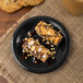 A Carlisle black melamine pie plate with two chocolate covered ice cream bars on it.