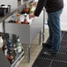 A man reaching for a brown bottle of alcohol in a Regency underbar ice bin.