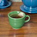 A green Fiesta china cup filled with tea and a tea bag.