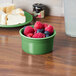 A white Fiesta ramekin filled with raspberries and blueberries on a table.