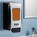 A GOJO manual high capacity soap dispenser on a wall.
