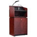 A mahogany podium with a wireless microphone and speakers.