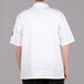 A man wearing a white Chef Revival short sleeve chef coat with bronze buttons.