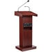 A mahogany wooden lectern with a microphone and speaker.