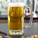 An Anchor Hocking beer mug filled with beer on a table.