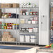 Regency chrome wire shelving unit in a large school kitchen with food and containers on the shelves.