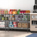 A Regency black wire shelf filled with drinks and boxes in a convenience store.