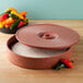A round red HS Inc. tortilla server with a lid open.