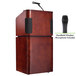 A wooden podium with a microphone and wireless handheld microphone on it.