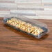 A Sabert clear plastic catering tray with a high dome lid over pastries on a table.