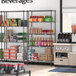 Regency black wire shelving unit in a convenience store with shelves of beverages and boxes.