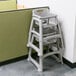 A Rubbermaid platinum high chair for babies in a hospital cafeteria.