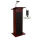 A mahogany podium with a wireless microphone and speaker.