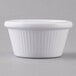 A close up of a Carlisle white fluted ramekin on a gray surface.