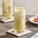 A glass of iced matcha green tea latte on a marble coaster.