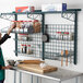 A woman wearing a green apron using a Metro SmartWall G3 worktable wall kit in a kitchen.