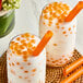 Two glasses of milk with Bossen Passion Fruit Bursting Boba and orange straws.