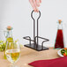 A Tablecraft Marbella black metal rack holding oil and vinegar over a table.