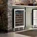 A stainless steel commercial wine cooler with a glass door built into a kitchen cabinet.