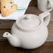 A Hall China ivory teapot with a lid on a table.