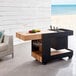 An Astella black mobile bar with wine glasses and a tray of wine on it.