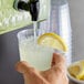 A person pouring Narvon Lemonade concentrate into a glass of liquid.